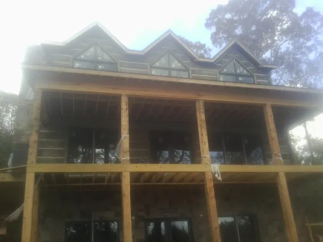 Dormers and porch framing on a large log home under construction — Roof Coating work by our crew in Orlinda