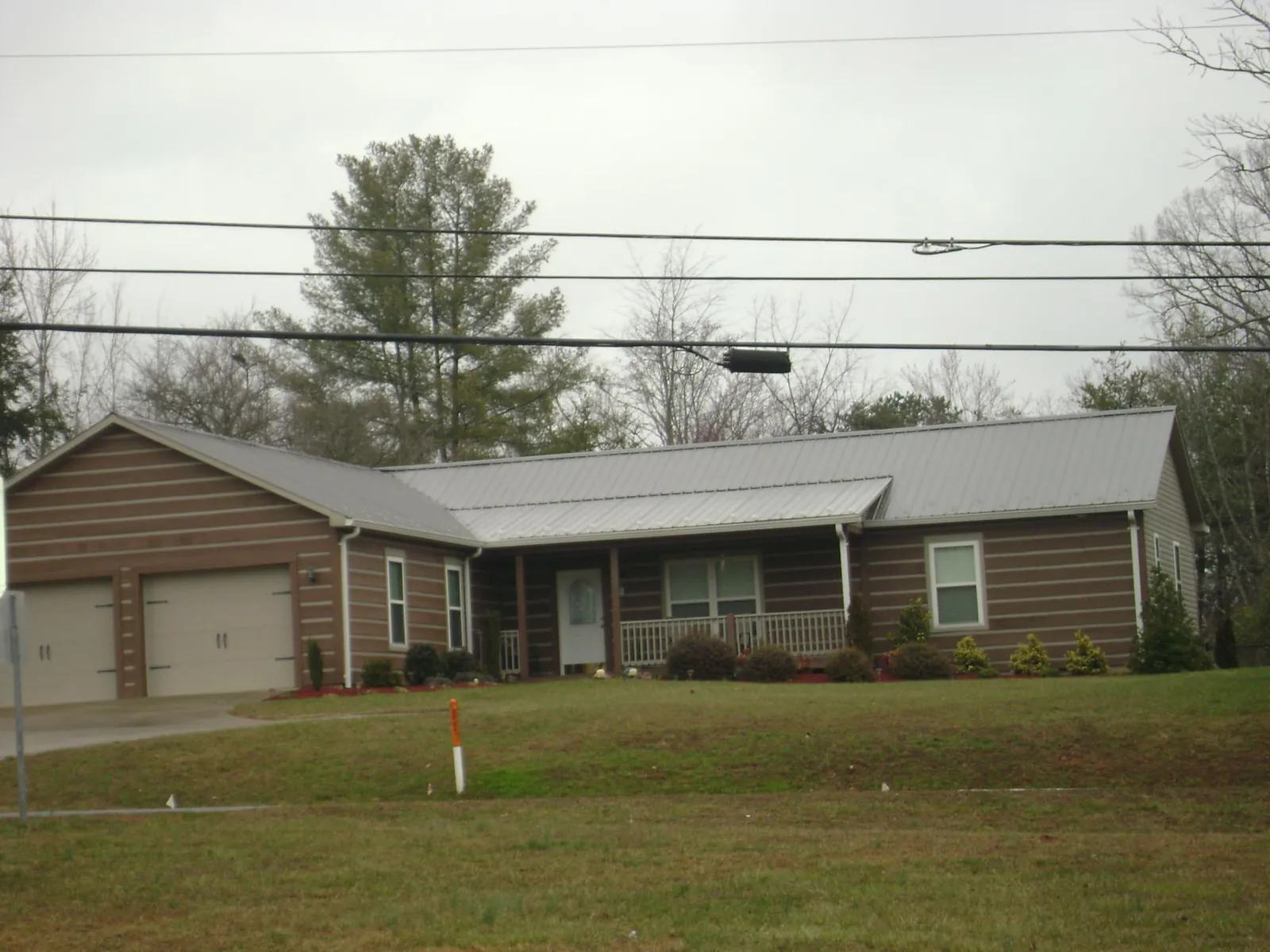 Gray metal roof on a log sided ranch home with a front porch in Orlinda