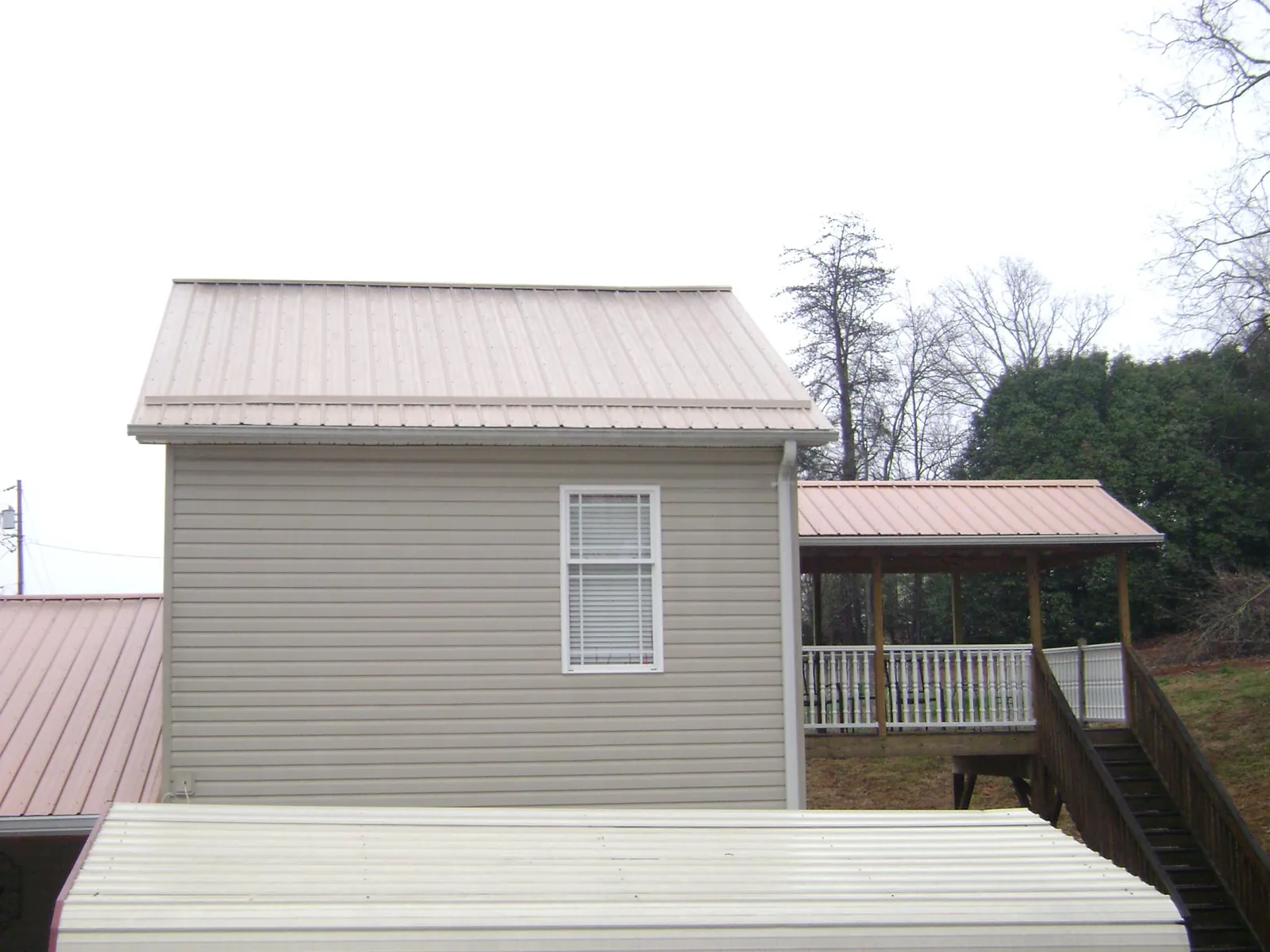 Tan metal roofs on a two story addition and attached porch, from a Roof Replacement job in Orlinda