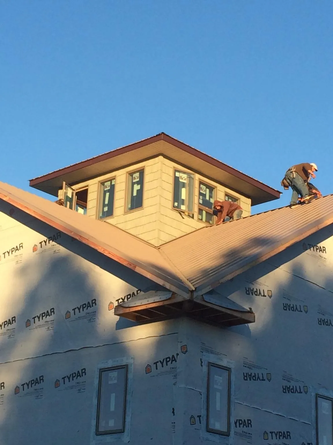 Roofers working around a rooftop cupola on a new metal roof at sunset — Roof Waterproofing in Orlinda by Roofing Brothers